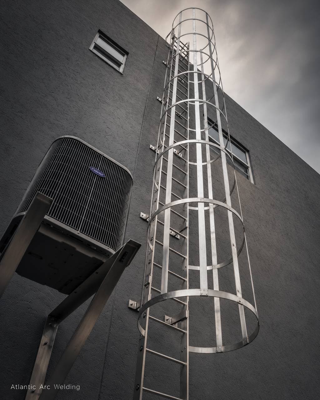Welded aluminum caged roof-access ladder